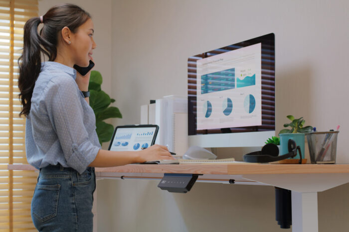 Woman stands while working thanks to Electric height-adjustable desk